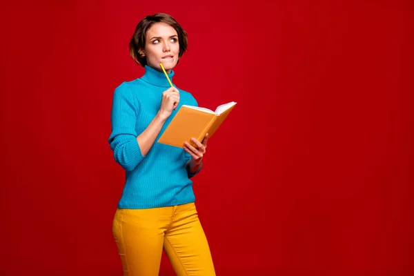 Πορτρέτο της έξυπνης κορίτσι γράψει έκθεση κατέχουν copybook σκεφτείτε σκέψεις δύσκολες ερωτήσεις δαγκώσει τα χείλη ματιά λάμψη copyspace φορούν μπλε πουλόβερ παντελόνι κίτρινο παντελόνι απομονωμένο κόκκινο χρώμα φόντο — Φωτογραφία Αρχείου