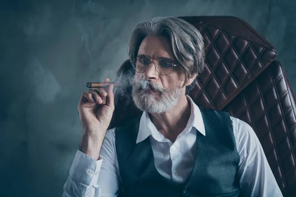 Gros plan photo de confiant cool intelligent macho vieil homme patron assis chaise fumée cigare rêve porter gilet chemise blanche isolé sur fond de couleur grise — Photo