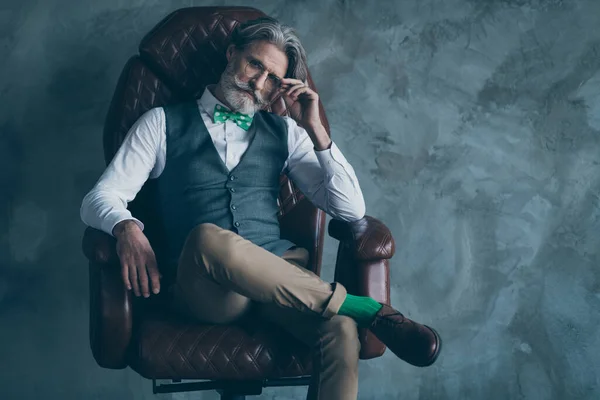 Photo de homme d'affaires macho senior barbe soignée assis confortable patron chaise look moderne usure spécifications élégant chemise gilet pantalon cravate chaussettes chaussures isolé béton gris couleur mur fond — Photo