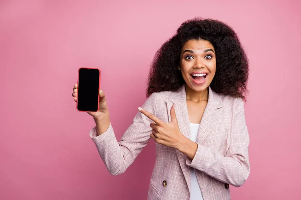 Foto de divertido emocionado teléfono de retención de la señora de la piel oscura demostrar nuevo modelo de teléfono inteligente precio de venta directa pantalla táctil dedo desgaste chaqueta a cuadros aislado fondo de color pastel — Foto de Stock