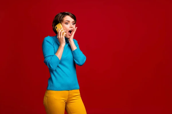 stock image Omg its unbelievable. Astonished impressed girl talk smartphone her fellow hear confidential private information scream touch hands face wear yellow pullover isolated red color background