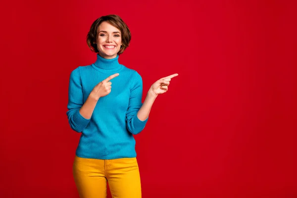 Retrato de positiva chica alegre promotor punto dedo dedo copia espacio sugieren anuncio selecto promoción desgaste jersey traje aislado sobre fondo de color rojo —  Fotos de Stock