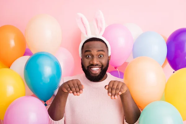 Photo of funny dark skin guy kolorowe dekoracje Wielkanoc strony trzymać ręce jak królicze łapki posłuszny osoba nosić sweter królicze uszy na balony różowy kolor tło — Zdjęcie stockowe