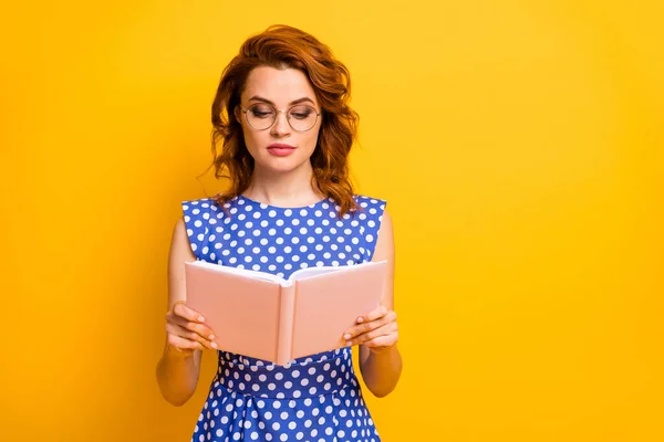 Fénykép gyönyörű lenyűgöző hölgy tartsa pszichológia könyv kezét nem mosolyog összpontosított olvasás kopás szemüveg polka-pont kék fehér ing elszigetelt sárga háttér — Stock Fotó