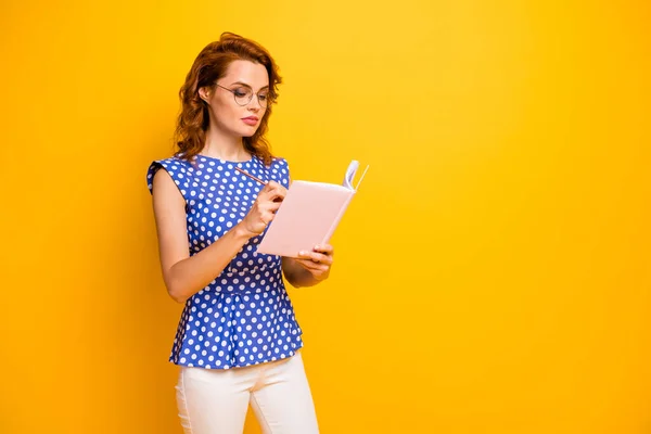 Foto de atractiva mujer de negocios asistente atentamente escribiendo notando consejo jefe copybook personal desgaste especificaciones polka-dot azul camisa pantalones blancos aislados color amarillo fondo —  Fotos de Stock