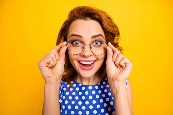 Lähikuva kuva kaunis nainen etsii maailman kautta uusia silmälaseja hämmästyttävä näkö visio avoin suu kulumista retro tyyli polka-piste sininen valkoinen paita eristetty keltainen väri tausta — kuvapankkivalokuva