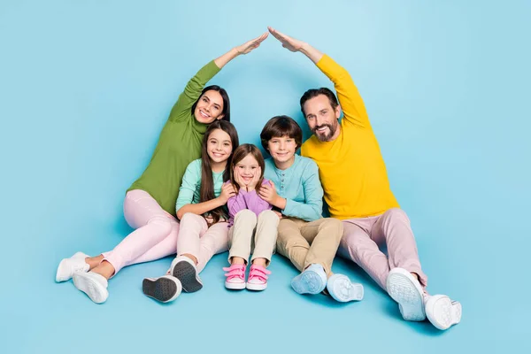 Retrato de agradable atractivo encantador cariñoso cuidadoso amable alegre alegre alegre gran familia completa sentado padres haciendo techo nuevo apartamento aislado en brillante brillo vivo vibrante color azul fondo — Foto de Stock