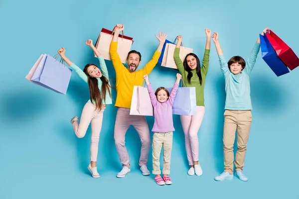 Pleine longueur taille du corps vue de belle attrayante joyeuse grande famille pleine sac de transport nouvelle chose vêtements boutique lever la main vers le haut isolé sur lumineux éclat vif fond de couleur bleu vif — Photo