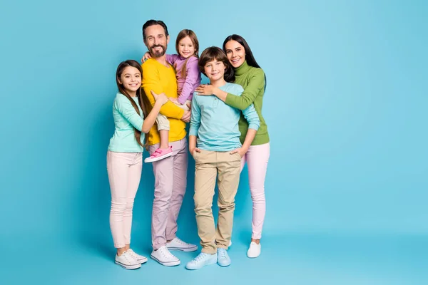 밝고 선명 한 파란색 배경에 고립된 아이들을 안고 있는 사랑스럽고 완벽하고 명랑 한 가족 아이들의 모습의 전체 몸길이 — 스톡 사진