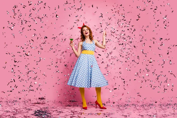 Full body photo of funky lady hold green cocktail theme retro party dancing star confetti falling wear headband dotted dress yellow tights red high-heels isolated pink color background — Zdjęcie stockowe