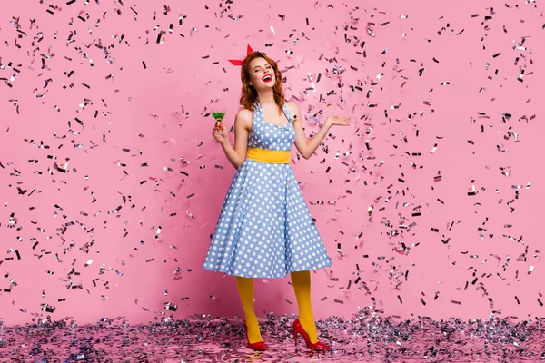 Full length photo of sexy funky lady hold green cocktail theme retro party enjoy confetti falling wear headband dotted dress yellow tights red high-heels isolated pink color background — Zdjęcie stockowe
