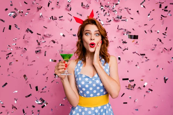 Photo of stunning lady hold green cocktail theme retro party got best costume nomination confetti falling wear red headband dotted dress yellow belt isolated pink color background