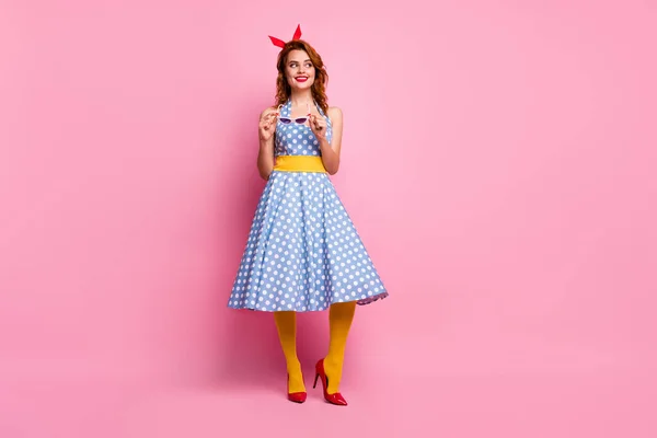 Full body photo of funny lady holding hands white sun specs looking flirty side empty space wear headband dotted dress red stilettos yellow tights isolated pink color background — Stockfoto