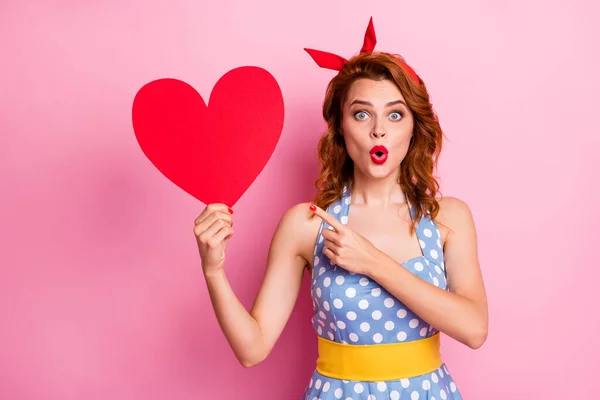 Photo of funny lady hold big red paper heart presenting invitation postcard open mouth indicate finger wear headband dotted dress yellow belt isolated pink color background — Stockfoto