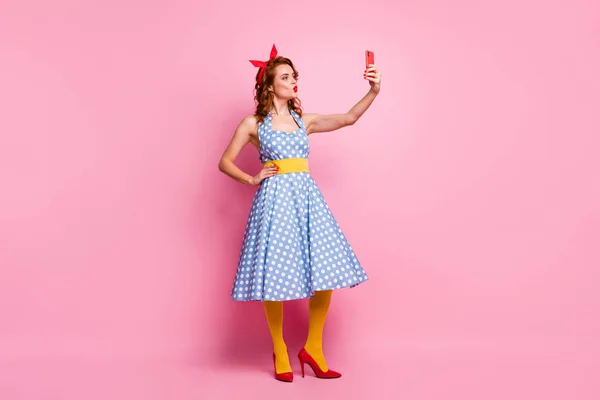 Full body photo of beautiful funny lady model hold telephone making selfies send air kiss wear headband dotted dress long skirt red stilettos yellow tights isolated pink color background — Stock fotografie