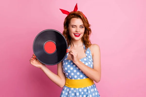 Photo of sexy flirty lady hold old fashion vinyl cd record bring collection single retro party winking eye wear dotted dress red headband yellow belt isolated pink color background — Stockfoto