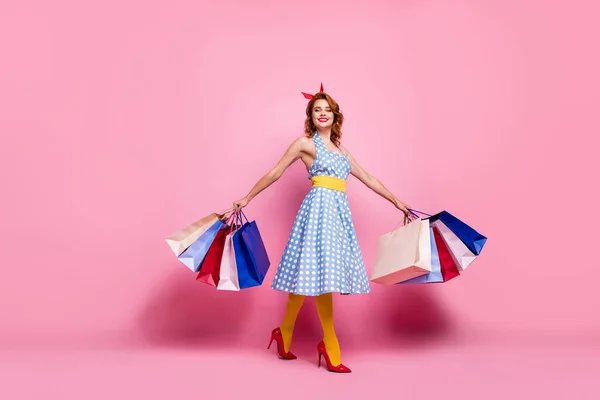 Full size photo cheerful tender elegant cute pretty girl summer weekend go shopping hold many bags enjoy purchase wear blue headband yellow tights red stilettos isolated pink color background — 스톡 사진