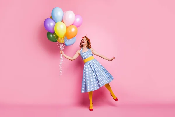 Full size photo of positive cheerful lady feel carefree enjoy fifty style rest relax hold many baloons laugh wear tights blue good look clothes isolated over pink color background — Stockfoto