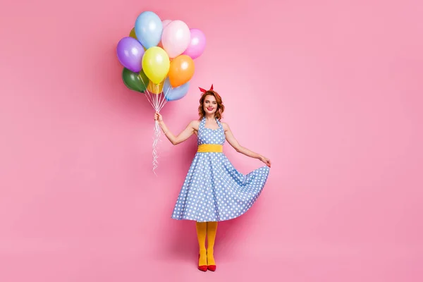 Full length photo of positive cheerful pretty sweet lady girl hold decoration helium baloons enjoy summer event touch blue polka-dot dress yellow tights isolated over pink color background — Stock Fotó