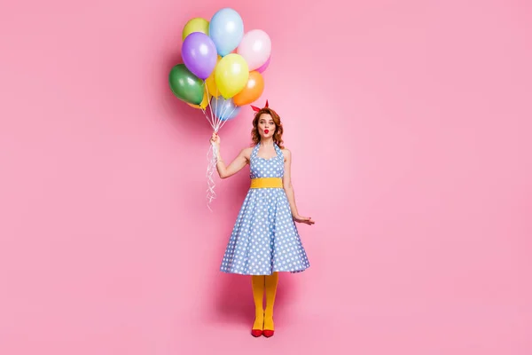 Fuld størrelse foto af drømmende elegant dame holde mange lyse farverige luft bolde baloon sende luft kys til hendes elskere bære blå polka-dot nederdel gule strømpebukser isoleret over lyserød farve baggrund - Stock-foto