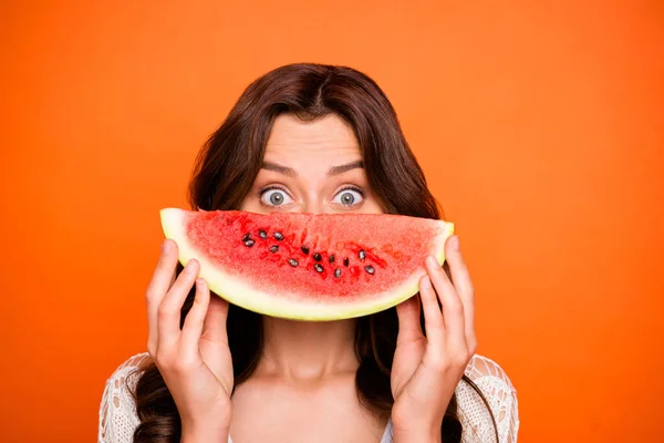 Photo of cheerful positive cute nice charming pretty girlfriend looking out of wedge of watermelon watching you playfully isolated over vivid color background — ストック写真