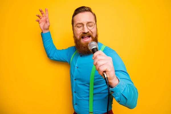 Portrait of imposing positive cool man hold mic sing song enjoy his rock-and-roll performance wear modern outfit isolated over bright color background — Stockfoto