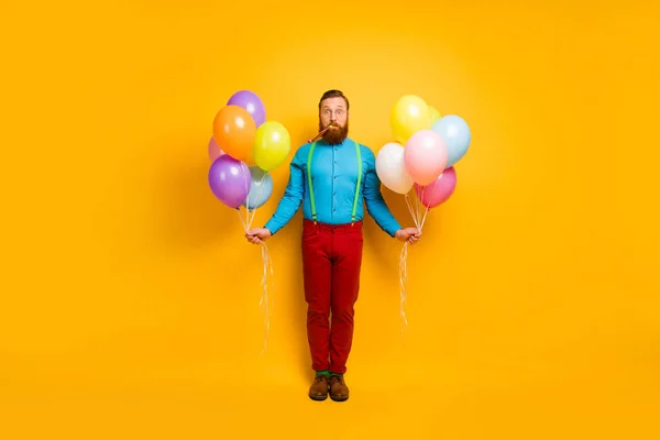 Foto de tamaño completo de divertido funky imponente celebrar muchos globos de helio silbato fiesta ruidosa celebrar disfrutar de aniversario desgaste verde ropa azul calzado aislado sobre fondo de color amarillo —  Fotos de Stock