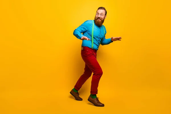 Foto de longitud completa de chico atractivo lento silenciar pasos ocultando novia haciendo visita sorpresa usar camisa azul tirantes verdes pantalones rojos calcetines calzado aislado color amarillo fondo —  Fotos de Stock