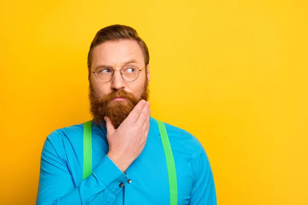Closeup photo of attractive strict red head boss guy arm on chin neat beard look doubts empty space wear specs bright blue shirt green suspenders isolated yellow color background — Φωτογραφία Αρχείου