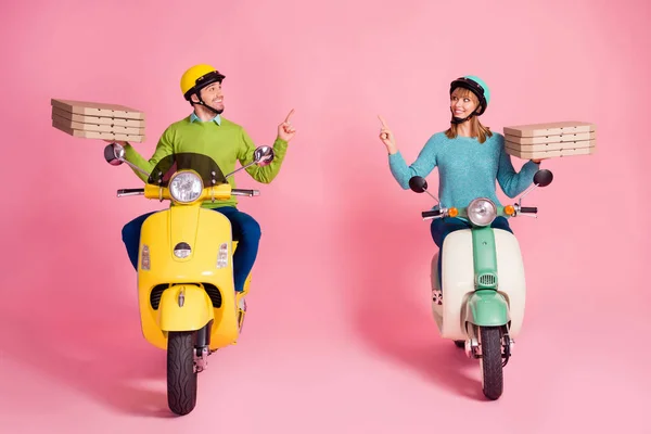 Full storlek foto av rolig dam kille kör två vintage moped bära papper pizza lådor direkt finger tomt utrymme kurir bära casual outfit huvudbonad isolerad rosa färg bakgrund — Stockfoto