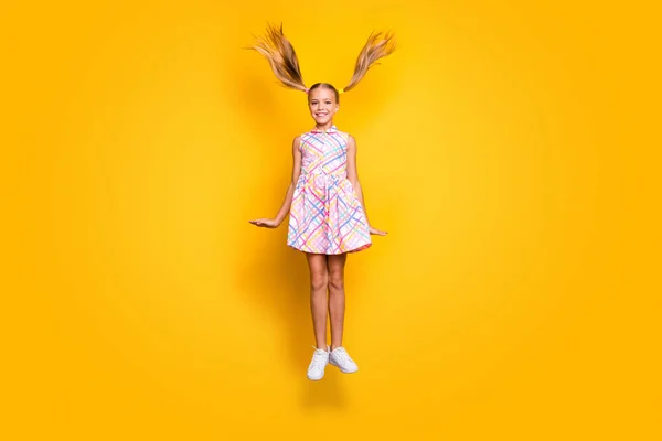 Full size photo of cheerful dreamy kid jump enjoy rest relax her hairdo fly wind blow wear style stylish trendy plaid skirt footwear isolated over yellow color background — Φωτογραφία Αρχείου