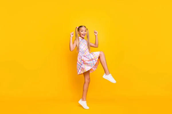 Full size profile photo of funny small lady good mood rejoicing classmates youth party raise fists leg wear checkered summer dress shoes isolated yellow bright color background — ストック写真
