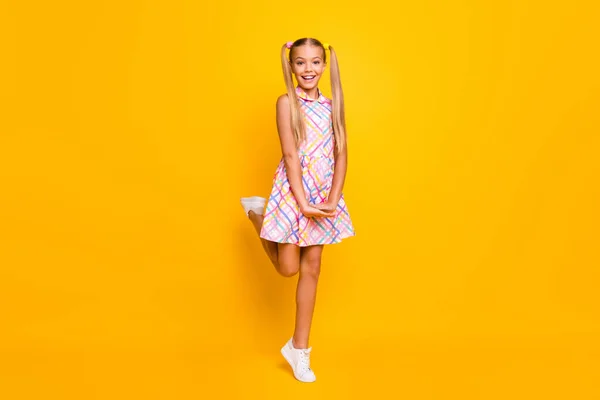 Full body photo of beautiful small lady tourist good mood pretty long tails playful walk street wear plaid summer dress white sneakers isolated yellow vibrant color background — Φωτογραφία Αρχείου