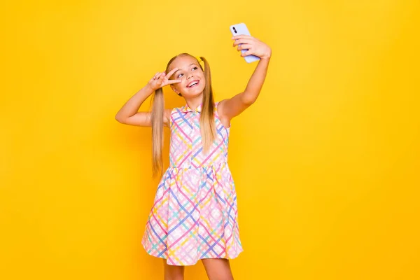 Foto de la señora bastante pequeña mantenga teléfono joven influencer haciendo selfies para el blog que muestra símbolo v-signo cerca de desgaste del ojo vestido de verano a cuadros aislado de color brillante de fondo —  Fotos de Stock