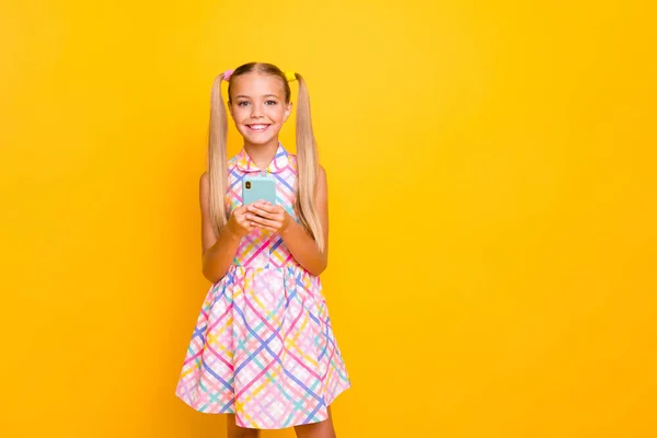 Photo of beautiful pretty little lady hold telephone young influencer write new post for own popular school theme blog wear checkered sun dress isolated bright yellow color background — Stockfoto