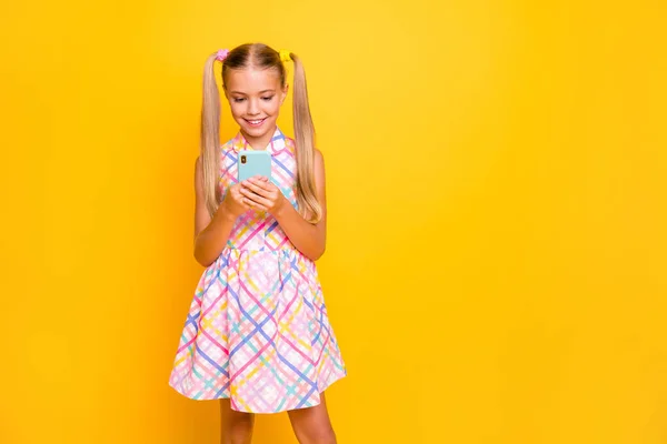 Photo of beautiful small lady hold telephone young influencer write new post for own popular modern blog wear checkered sun dress isolated bright yellow color background — Stockfoto