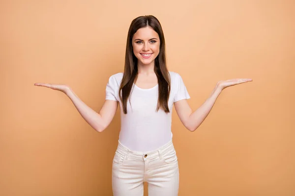 Retrato de niña alegre positiva promotor de la mano comparar anuncios recomiendan sugerir ropa promocional selecta buena apariencia traje aislado sobre fondo de color beige — Foto de Stock