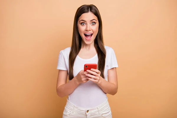 Portrait astonished cheerful girl use smartphone get incredible social network notification impressed scream unbelievable unexpected wear good look outfit isolated beige color background — Stockfoto