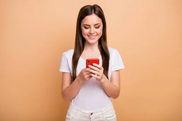 Портрет позитивної веселої дівчини використовує смартфон, читає інформацію про соціальну мережу, насолоджується веденням блогу, одягаючи гарний вигляд одягу, ізольованого на пастельному кольоровому фоні — стокове фото