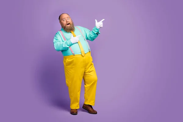 Full size photo of positive crazy funny fat man point index finger copyspace present sales discount wear teal turquoise shirt pink suspenders footwear isolated over purple color background — ストック写真
