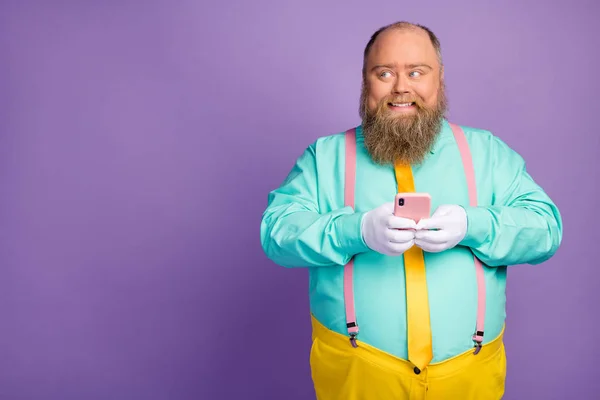Portrait of positive gentleman blogger with big belly use cellphone enjoy texting social media feedback wear turquoise pink pants shine isolated over violet color background — Stok Foto