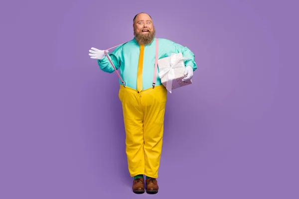 Full body photo energetic crazy funky man big abdomen hold dotted package box he give wife 14-february event date pull suspenders wear turquoise pants isolated purple color background — Stok fotoğraf