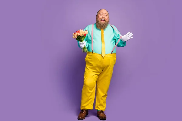 Full size photo positive crazy fat funky man hold blossom bouquet pull pink suspenders enjoy 8-march 14-february celebration wear turquoise pants bright shine isolated violet color background — ストック写真