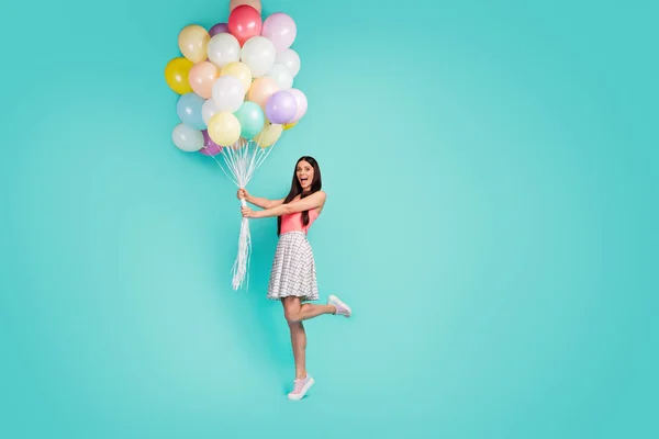 Full body photo of cheerful crazy funny girl hold many air baloons enjoy festive anniversary celebration wear pastel tank-top sneakers isolated over turquoise color background — 스톡 사진