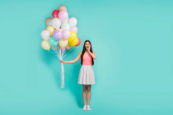 Full size photo of astonished girl celebrate festive event impressed by air baloons touch hands face scream wow omg wear pastel singlet footwear isolated over teal color background — 스톡 사진