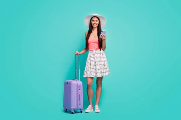 Full size photo positive girl tourist use cellphone book taxi service hold purple suitcase enjoy travel weekend wear white plaid checkered skirt pink singlet isolated pastel teal color background — 图库照片
