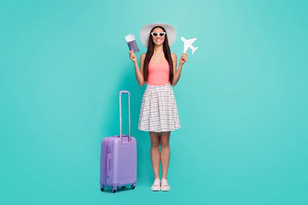 Full size photo positive girl ready travel summer weekend hold white papercard plane documents have big violet suitcase wear pink tank-top sunglass sneakers isolated turquoise color background — Stockfoto