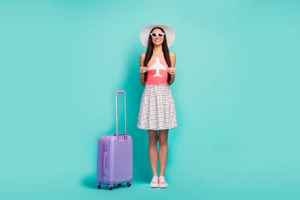Foto de longitud completa de chica alegre positiva listo viajar al extranjero en avión blanco disfrutar de fin de semana de viaje tienen maleta púrpura usar gafas de sol rosa calzado singlete aislado color verde azulado fondo —  Fotos de Stock