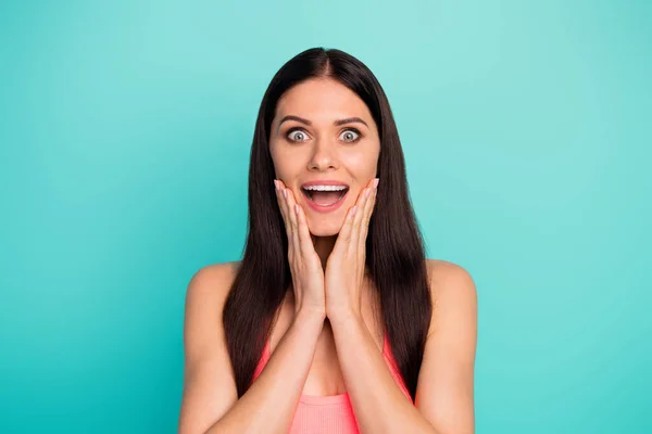 Portrait of astonished positive cheerful girl enjoy listening wonderful spring time bargains news touch hands face wear pastel singlet isolated over green color background — Stockfoto