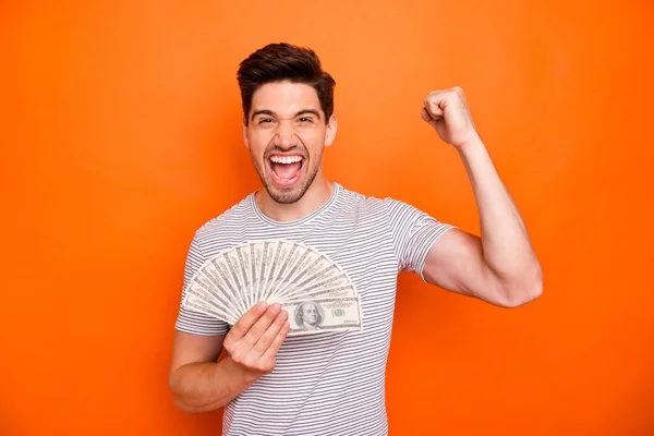 I am rich. Photo of funny attractive guy hold hands fan of bucks first currency salary raise fist screaming wear striped t-shirt isolated bright orange color background — Stock Photo, Image